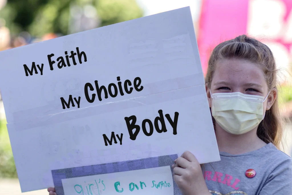 Abortion-Protestor-aiden-frazier-unsplash Girl holding sign that says, "My Faith, My Choice, My Body"