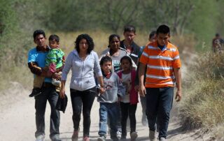 Photo of migrant family walking on dusty road in Rio Grande Valley, TX