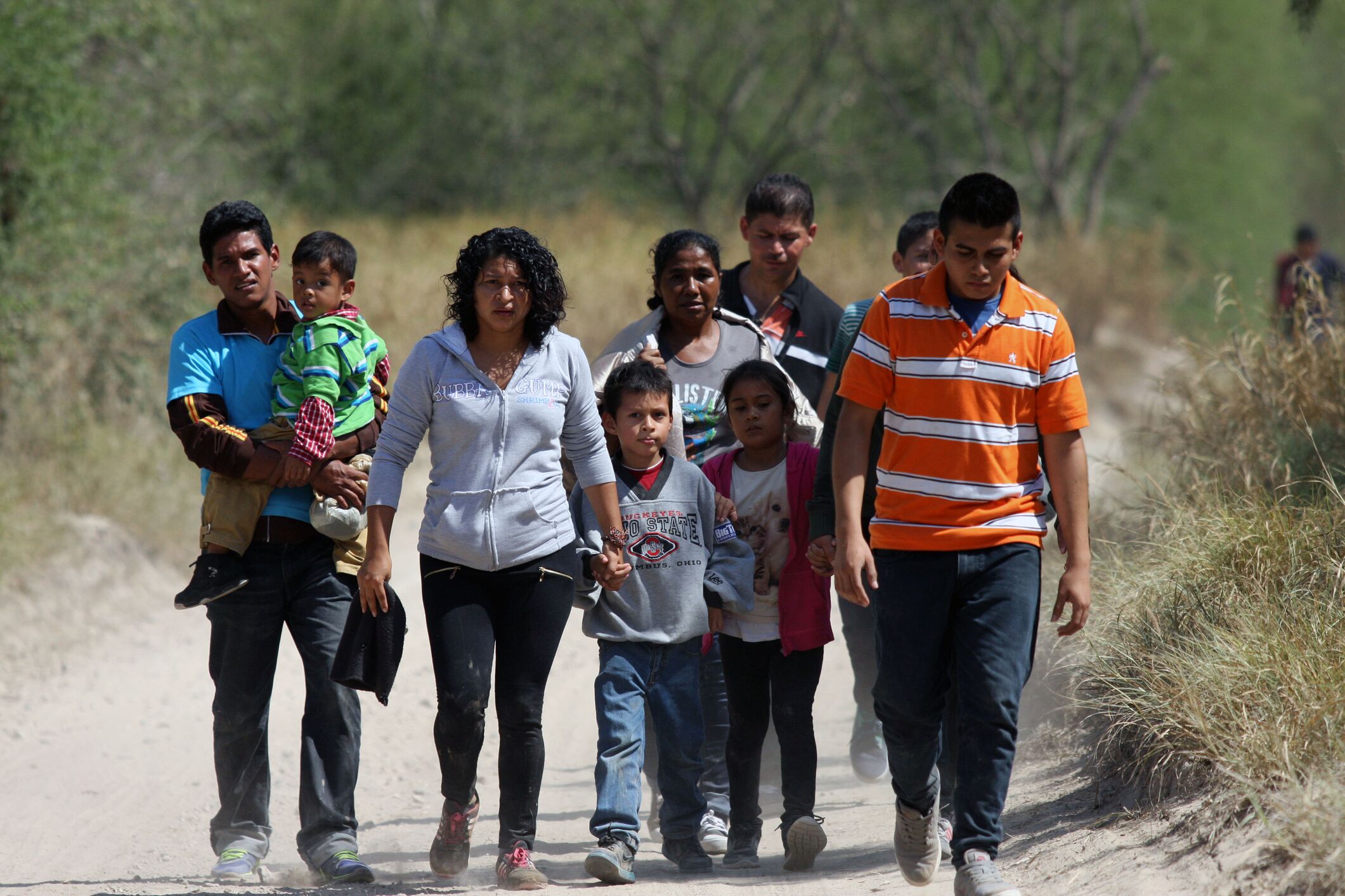 Photo of migrant family walking on dusty road in Rio Grande Valley, TX
