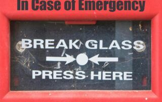 Image of an alarm that reads, "In case of emergency, break glass. Press here."