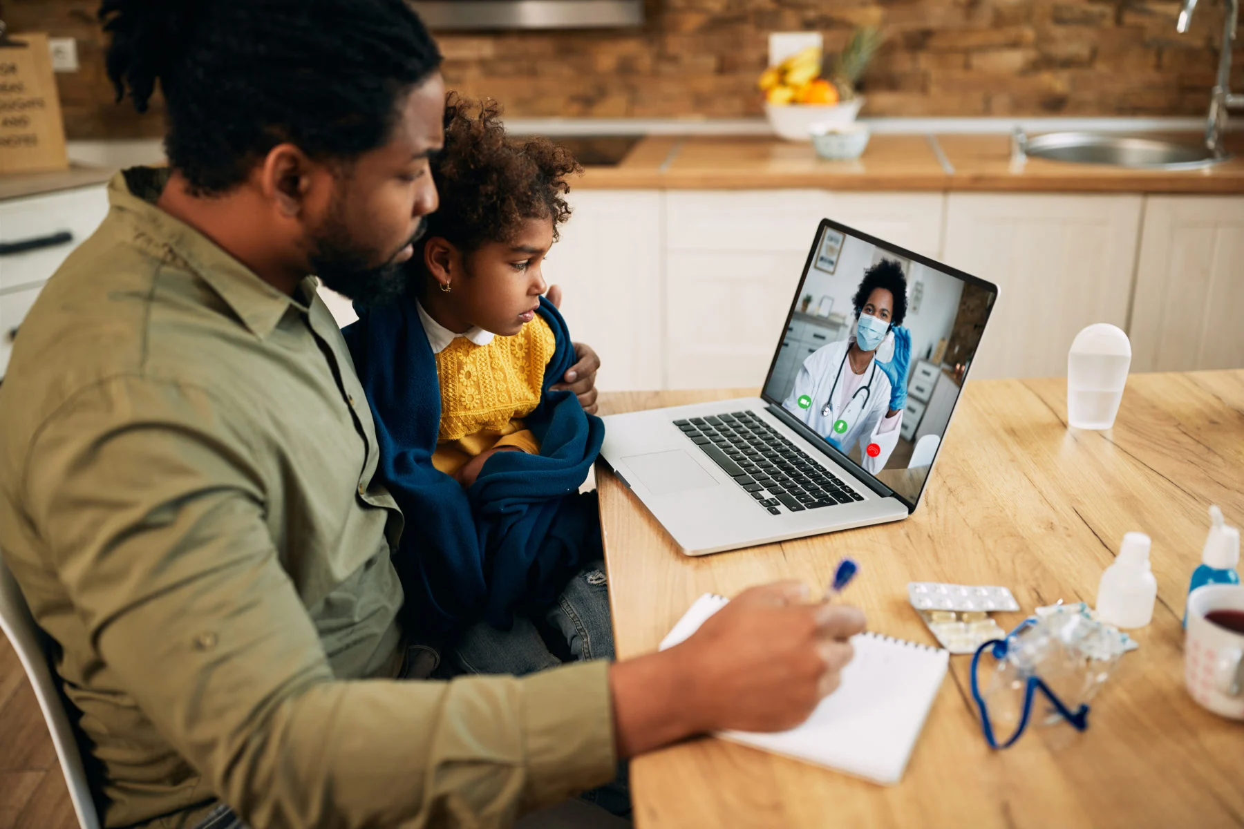Father and daughter having video call with family doctor due to coronavirus pandemic. Father and daughter on telehealth call